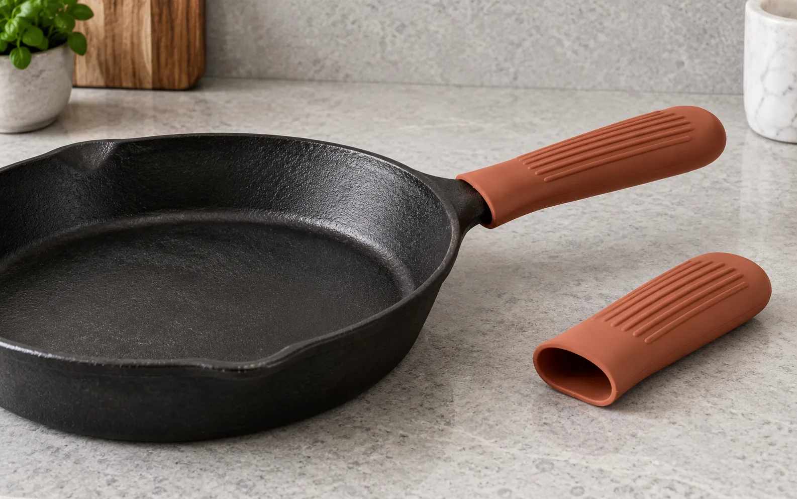Terracotta silicone sleeve fitted over a cast iron skillet handle with a second open-end sleeve beside it