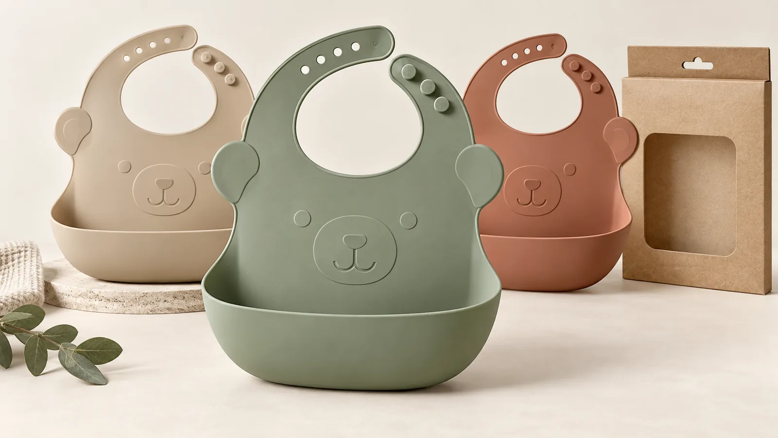 Dusty sage sand and terracotta animal-shaped silicone pocket bibs with molded bear-face relief